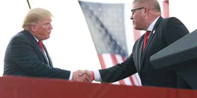 State Sen. Darren Bailey, an Illinois gubernatorial candidate, greets Donald Trump after receiving an endorsement from the former president at a rally at the Adams County Fairgrounds June 25, 2022, in Mendon, Ill. 