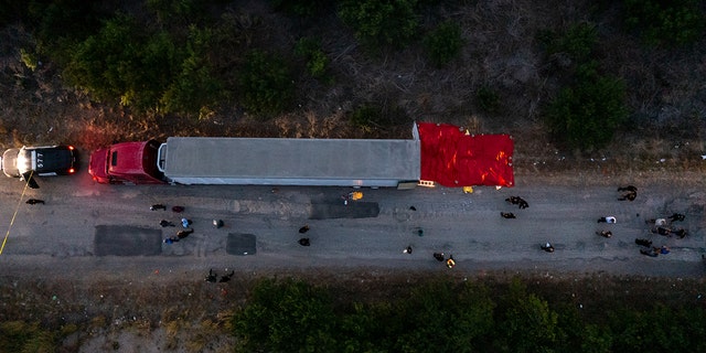 In this aerial view, members of law enforcement investigate a tractor trailer on June 27, 2022, in San Antonio. Homeland Security Investigations said 48 migrants were declared deceased at the scene, while several others later died at hospitals, raising the death toll to at least 53 people who perished.