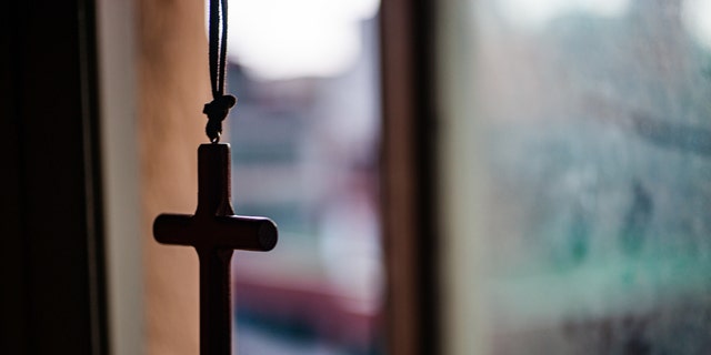 Cross necklace hanging in front of the window