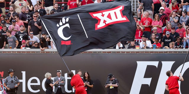 A Cincinnati Bearcats cheerleader waves a flag with the Cincinnati Bearcats and Big 12 logos during a game against the Murray State Racers at Nippert Stadium Sept. 11, 2021, in Cincinnati.