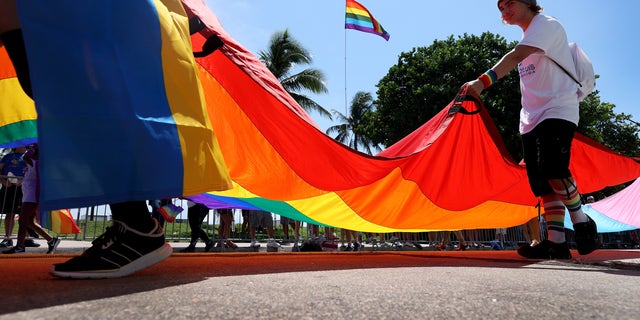 People carry the Rainbow Flag as they participate in the Miami Beach Pride Parade along Ocean Drive on September 19, 2021, in Miami Beach, Florida.