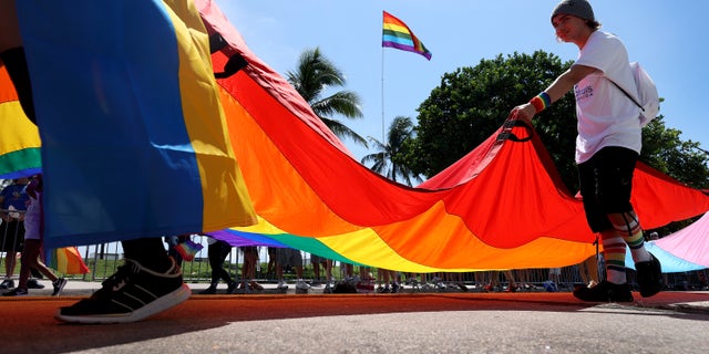 People carry the Rainbow Flag as they participate in the Miami Beach Pride Parade along Ocean Drive on September 19, 2021, in Miami Beach, Florida.