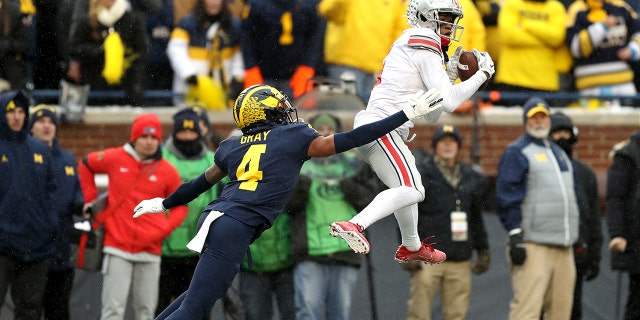 Garrett Wilson #5 of the Ohio State Buckeyes catches a pass as Vincent Gray #4 of the Michigan Wolverines defends in the fourth quarter during the game at Michigan Stadium on Nov. 27, 2021 in Ann Arbor, Michigan. 