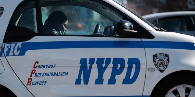 A NYPD officer sits in a marked vehicle.