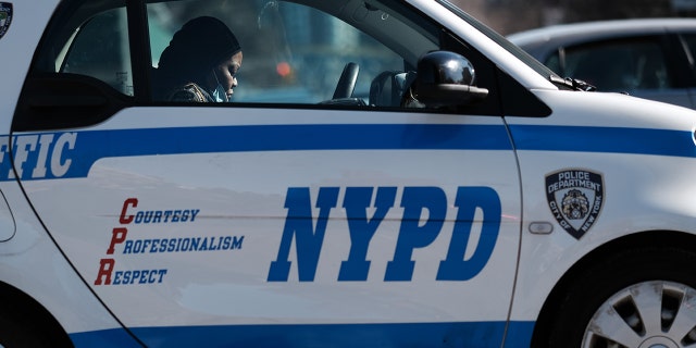 An NYPD officer sits in a marked vehicle.