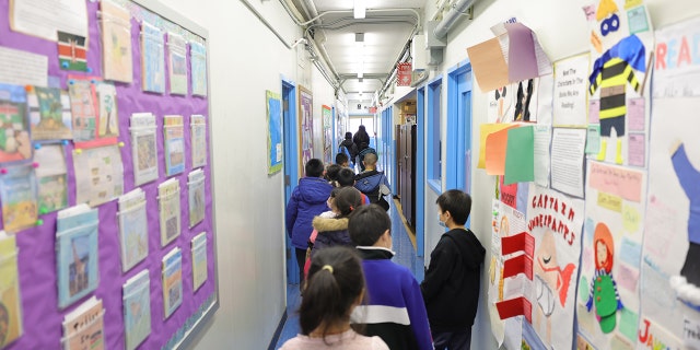 Students are led to their classroom by Marisa Wiezel (who is related to the photographer), a teacher at Yung Wing School P.S. 124, on March 7, 2022, in New York City.