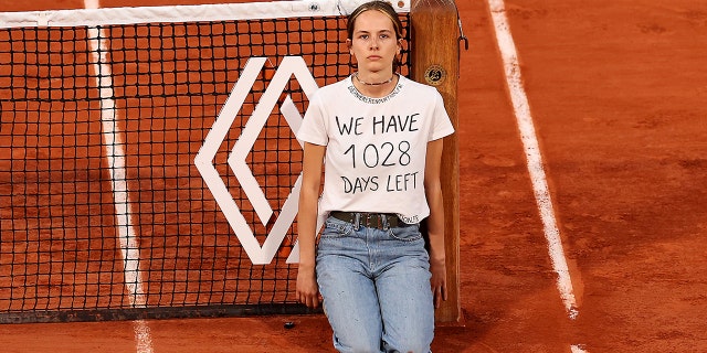 A protester ties herself to the net during a men's singles semifinal match between Marin Cilic of Croatia and Casper Ruud of Norway at the 2022 French Open at Roland Garros on June 3, 2022, in Paris. 