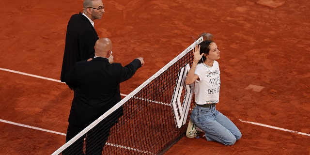 A protester ties herself to the net during a men's singles semifinal match between Marin Cilic of Croatia and Casper Ruud of Norway at the 2022 French Open at Roland Garros June 3, 2022, in Paris. 