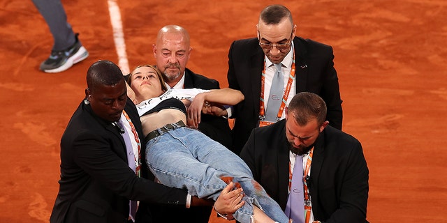 A protester is taken off the court after tying herself to the net during a men's semi-final match between Marin Cilic of Croatia and Casper Ruud of Norway at the French Open 2022 at Roland Garros on June 3, 2022 in Paris. 