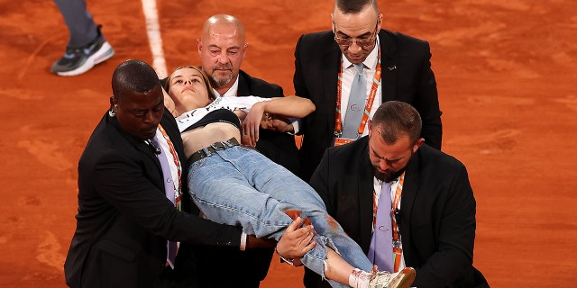 En demonstrant bliver båret væk fra banen efter at have bundet sig til nettet under semifinalekampen for herresingle mellem kroatiske Marin Cilic og norske Kasper Ruud ved French Open 2022 på Roland Garros den 3. juni 2022 i Paris.