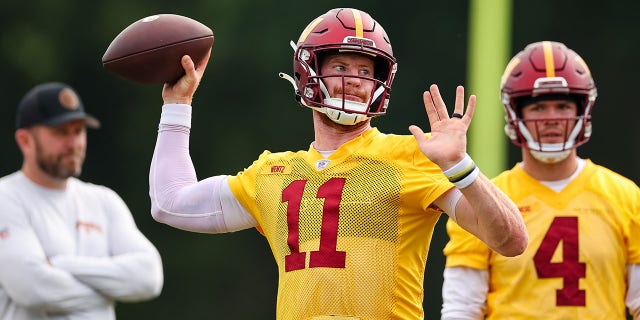 Offensive coordinator Scott Turner and Taylor Heinicke (4) watch as Carson Wentz (11) of the Washington Commanders throws during practice at INOVA Sports Performance Center June 8, 2022, in Ashburn, Va.