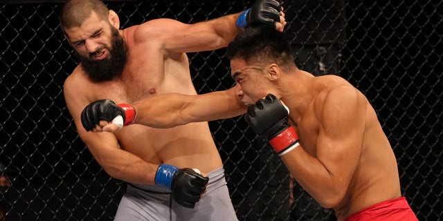 (R-L) Zhang Mingyang of China punches Tuco Tokkos of England during the Road to UFC event at Singapore Indoor Stadium on June 09, 2022 in Singapore.