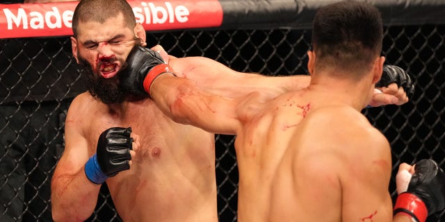 (R-L) Zhang Mingyang of China punches Tuco Tokkos of England during the Road to UFC event at Singapore Indoor Stadium on June 09, 2022 in Singapore.