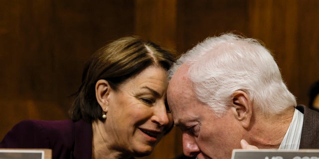 Sen. Amy Klobuchar, D-Minn., speaks to Sen. John Cornyn, R-Texas.