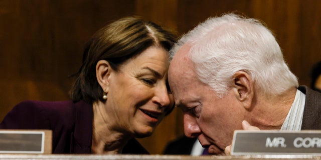 Sen. Amy Klobuchar, D-Minn., speaks to Sen. John Cornyn, R-Texas.