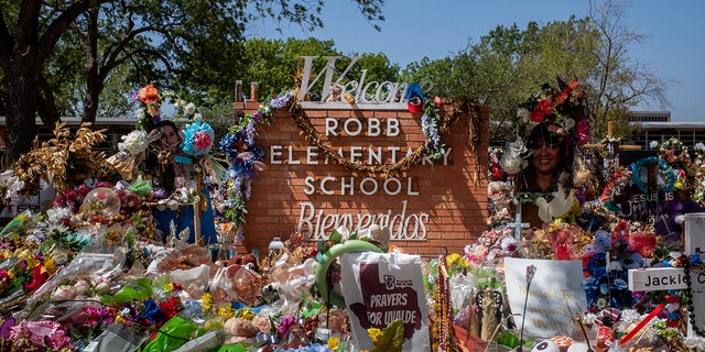 The Robb Elementary School sign is covered in flowers and gifts on June 17, 2022, in Uvalde, Texas.