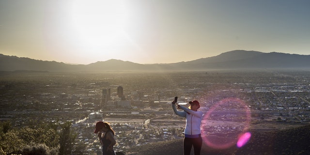 A woman takes a selfie with a smartphone from the top of Tumamoc Hill during sunrise on May 13, 2015 in Tucson, Arizona. (BRENDAN SMIALOWSKI/AFP via Getty Images)
