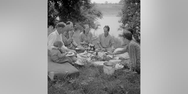 A family enjoys a July 4th fish fry during a picnic, circa 1940.