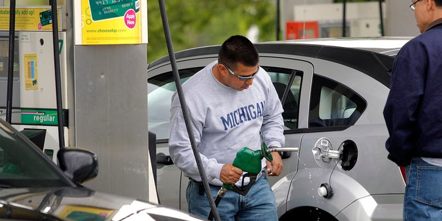 This file photo shows a customer removing the nozzle of a gas pump from his car after getting gas at a BP gas station in Romulus, Michigan. 
