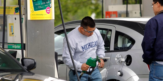 This file photo shows a customer removing the nozzle of a gas pump from his car after getting gas at a BP gas station in Romulus, Michigan. 