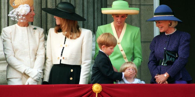 Prinz Harry legt zusammen mit der Prinzessin von Wales und anderen Mitgliedern der königlichen Familie der zweijährigen Prinzessin Beatrice die Hände auf, um heute Morgen an ihrem sechsten Geburtstag die Parade zum 50. Jahrestag des britischen Krieges zu sehen. 