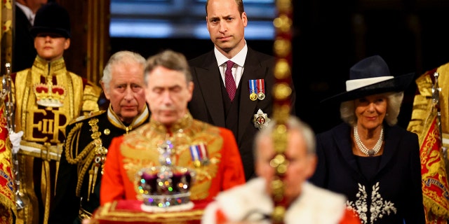 Prince Charles, Prince of Wales; Camilla, Duchess of Cornwall; and Prince William (C) proceed behind the Imperial State Crown through the Royal Gallery for the State Opening of Parliament in the House of Lords at the Palace of Westminster May 10, 2022, in London.