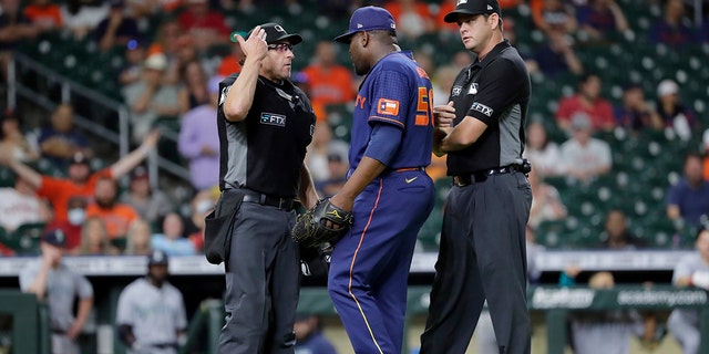 Houston Astros relief pitcher Hector Neris, middle, protests his ejection with umpires Chris Guccione, left, and Jordan Baker, right, after Neris threw at the head of Seattle Mariners batter Eugenio Suarez during the ninth inning of a baseball game Monday, June 6, 2022, in Houston.