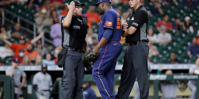 Houston Astros relief pitcher Hector Neris, middle, protests his ejection with umpires Chris Guccione, left, and Jordan Baker, right, after Neris threw at the head of Seattle Mariners batter Eugenio Suarez during the ninth inning of a baseball game Monday, June 6, 2022, in Houston.