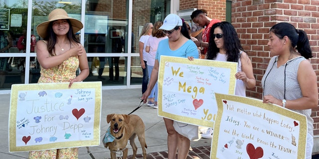 Johnny Depp fans hold signs while waiting for the verdict in his defamation trial against Amber Heard.