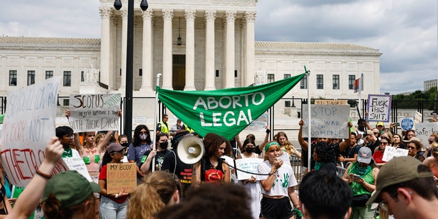 Pro-choice activists stand in front of the Supreme Court with a sign reading, 'Aborto Legal.'