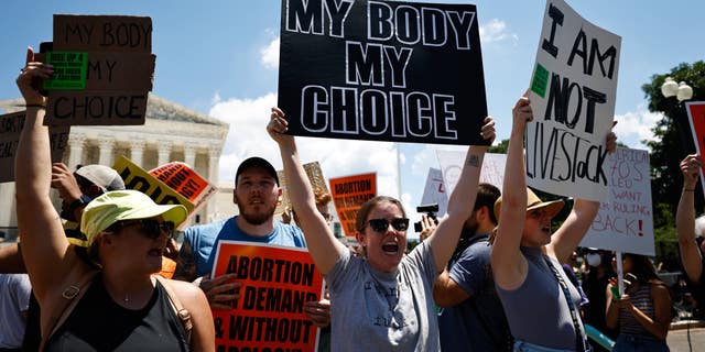 Protesters stand in front of the Supreme Court building with pro-choice signs.