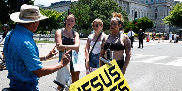 Women are shown holding a "Jesus Saves" sign in Washington, D.C.