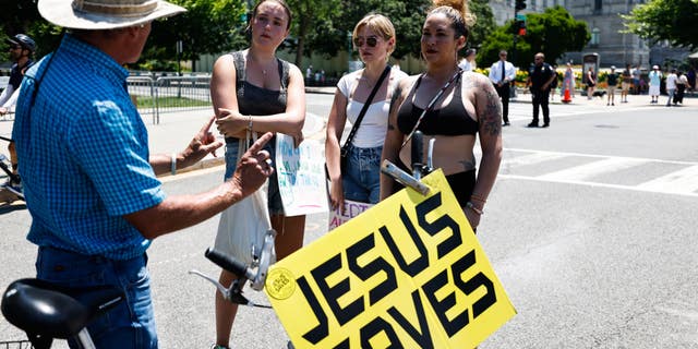 Women are shown holding a "Jesus Saves" sign in Washington, D.C.