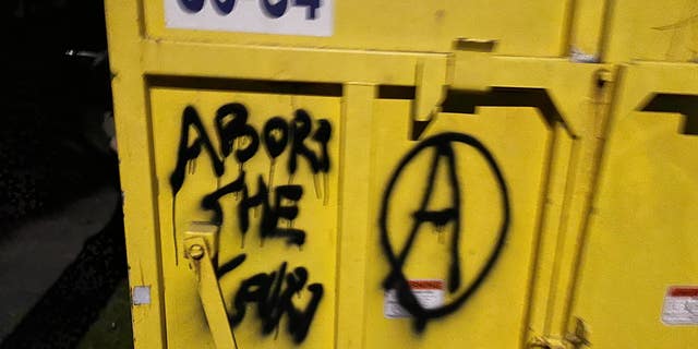 Another message the group spray-painted on a storage box appears to say: "Abort the court."