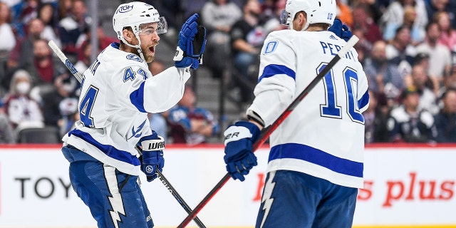 Il difensore del Tampa Bay Lightning John Rutta (44) festeggia con il destro Corey Perry (10) dopo aver segnato il suo primo gol nella finale della Stanley Cup 5 tra Tampa Bay Lightning e Colorado Avalanche al Ballroom di Denver, in Colorado, il 24 giugno.  , 2022.