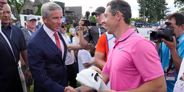 Rory McIlroy, front right, shakes hands with PGA Commissioner Jay Monahan after winning the Canadian Open golf tournament in Toronto, Sunday, June 12, 2022. 