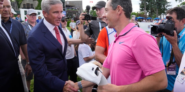 Rory McIlroy, front right, shakes hands with PGA Commissioner Jay Monahan after winning the Canadian Open golf tournament in Toronto, Sunday, June 12, 2022. 