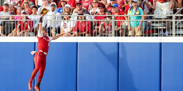 Jayda Coleman #24 of the Oklahoma Sooners makes a jumping catch during the first inning against the Texas Longhorns during the Division I Womens Softball Championship held at ASA Hall of Fame Stadium on June 9, 2022 in Oklahoma City, Oklahoma.