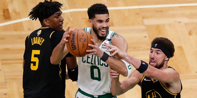 Boston Celtics forward Jayson Tatum (0) battles for a rebound against Golden State Warriors center Kevon Looney (5) and guard Klay Thompson (11) during the fourth quarter of Game 3 of basketball's NBA Finals, Wednesday, June 8, 2022, in Boston. 