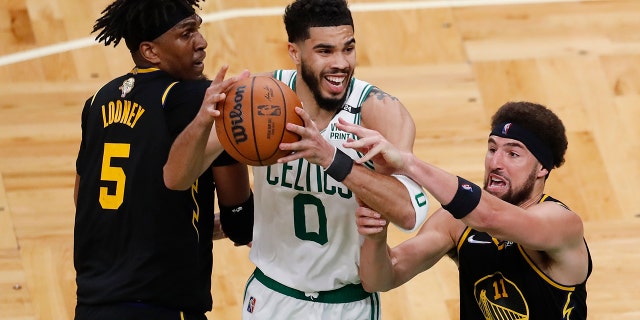 Boston Celtics forward Jayson Tatum (0) battles for a rebound against Golden State Warriors center Kevon Looney (5) and guard Klay Thompson (11) in the fourth quarter of Game 3 of the NBA Finals basketball- ball, Wednesday, June 8, 2022, in Boston.