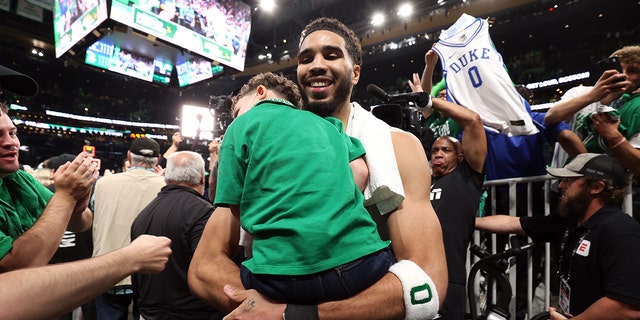 Jayson Tatum of the Celtics carries his son, Deuce, after the NBA Finals game on June 8, 2022, in Boston.