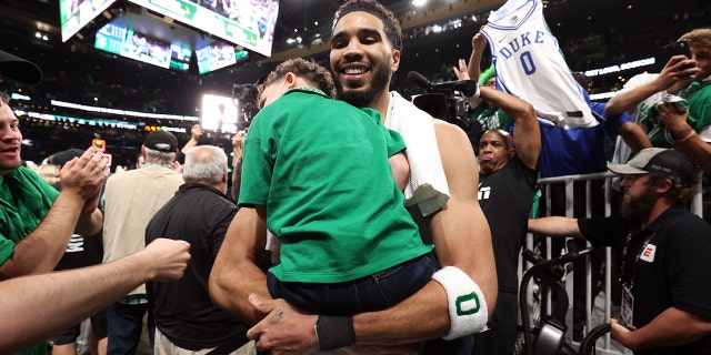 Jayson Tatum of the Celtics carries his son, Deuce, after the NBA Finals game on June 8, 2022, in Boston.