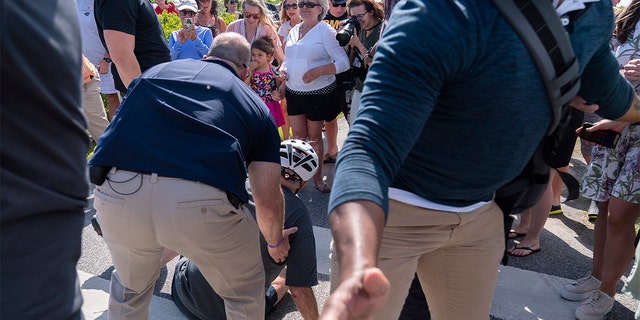 President Biden is helped by Secret Service agents after falling from his bike as he stopped to greet a crowd on a trail at Gordons Pond in Rehoboth Beach, Del., Saturday, June 18, 2022. 