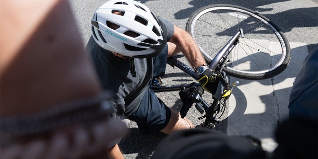 President Biden falls off his bicycle as he approaches well-wishers following a bike ride at Gordon's Pond State Park in Rehoboth Beach, Delaware, on June 18, 2022. 