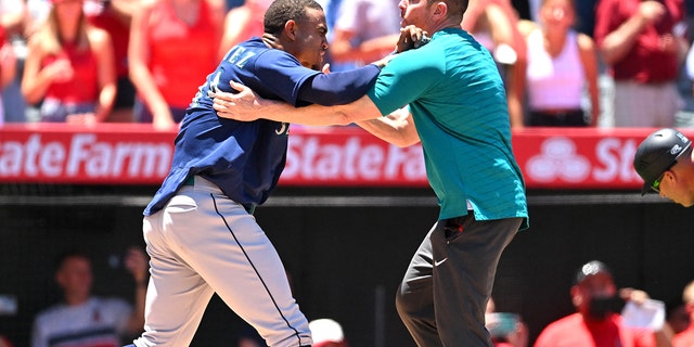 Jun 26, 2022; Anaheim, カリフォルニア, 米国;  Seattle Mariners strength coach James Clifford holds back center fielder Julio Rodriguez (44) during a benches clearing brawl with the Los Angeles Angels in the second inning at Angel Stadium.