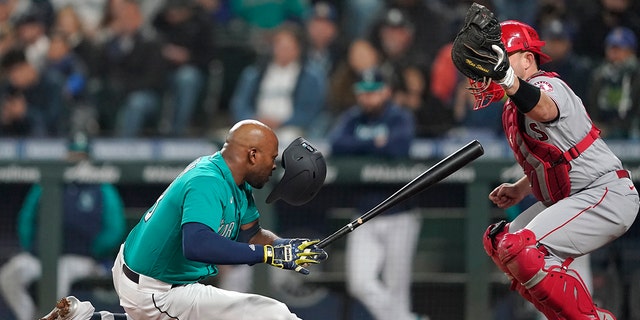 Seattle Mariners' Justin Upton, left, goes down after being hit by a pitch as Los Angeles Angels catcher Max Stassi looks on during the fifth inning of a baseball game, Friday, June 17, 2022, in Seattle. Upton left the game after the injury. 