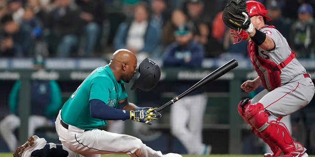 Seattle Mariners' Justin Upton, left, goes down after being hit by a pitch as Los Angeles Angels catcher Max Stassi looks on during the fifth inning of a baseball game, Friday, June 17, 2022, in Seattle. Upton left the game after the injury.
