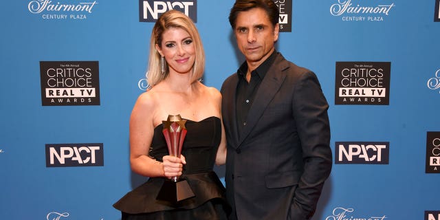 Kelly Rizzo, who accepted The Impact Award on behalf of the late Bob Saget, and John Stamos pose during the Fourth Annual Critics Choice Real TV Awards at Fairmont Century Plaza on June 12, 2022 in Los Angeles, California.