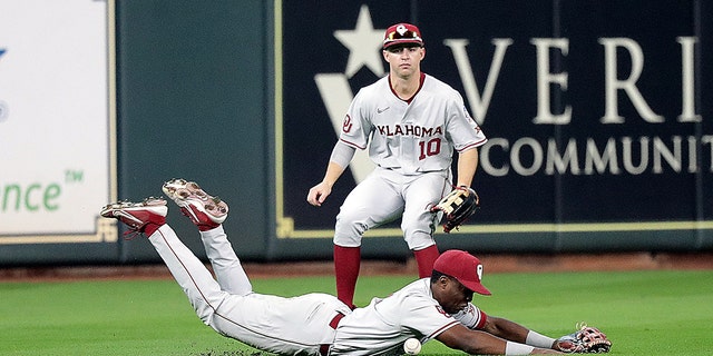 Kendall Pettis of the Oklahoma Sooners, foreground, comes up short after diving for a line drive as Tanner Treadaway backs him up against the UCLA Bruins during the Shriners Children's College Classic at Minute Maid Park March 5, 2022, in Houston.