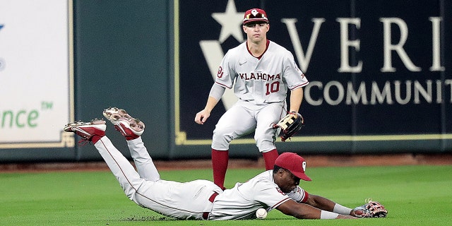 Kendall Pettis of the Oklahoma Sooners, foreground, comes up short after diving for a line drive as Tanner Treadaway backs him up against the UCLA Bruins during the Shriners Children's College Classic at Minute Maid Park March 5, 2022, in Houston.